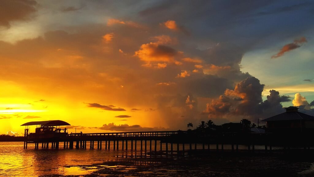 silhouette buildings by sea against sky sunset